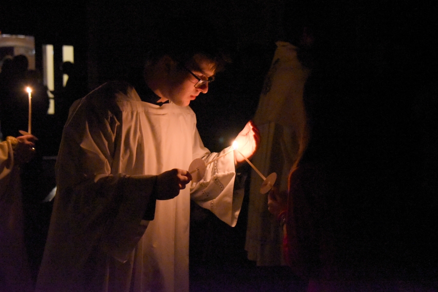 An altar server lights his candle from the Easter candle.