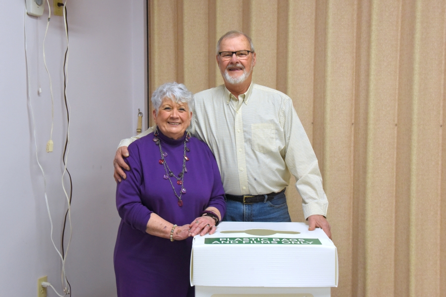 Ann Williams and Boyd Smith stand next to a recycling box.