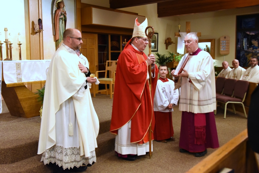 Bishop Robert Deeley prays with Father Steven Cartwright and Msgr. Marc Caron beside him.