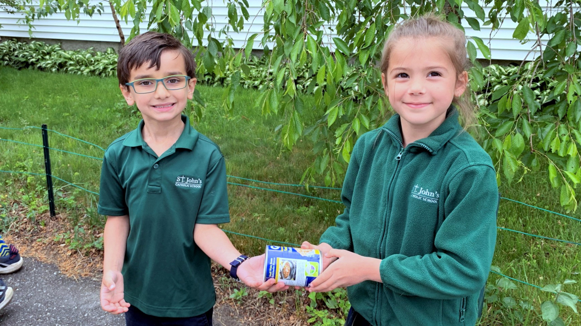 Two students hand off a can of food.