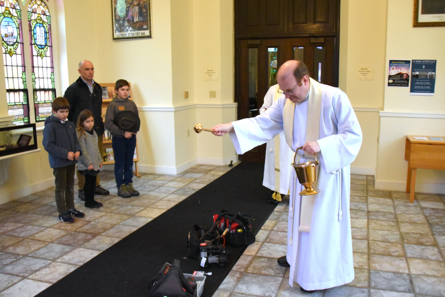 Father Kevin Upham sprinkles the tools with holy water.