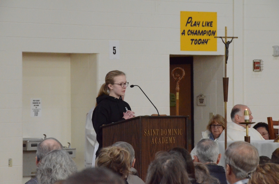 A student reading from the podium during mass