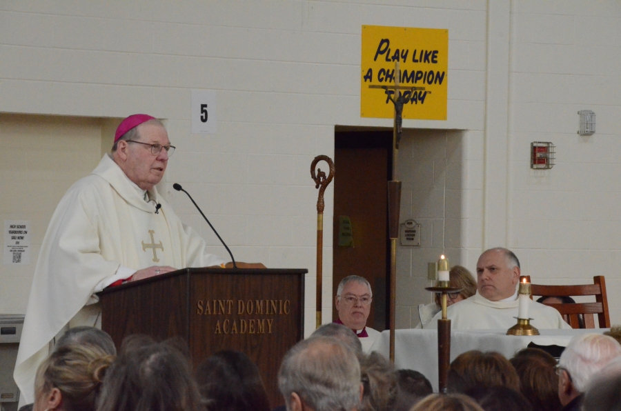 The bishop standing at the podium offers his homily to the crowd during the mass
