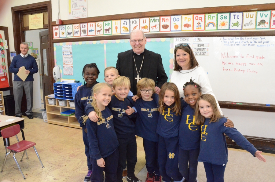 Eight students and a teacher pose for a photo with the bishop