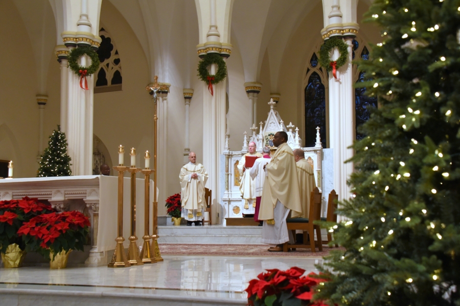 Bishop Deeley in the sanctuary, wider view with a Christmas tree in the foreground.