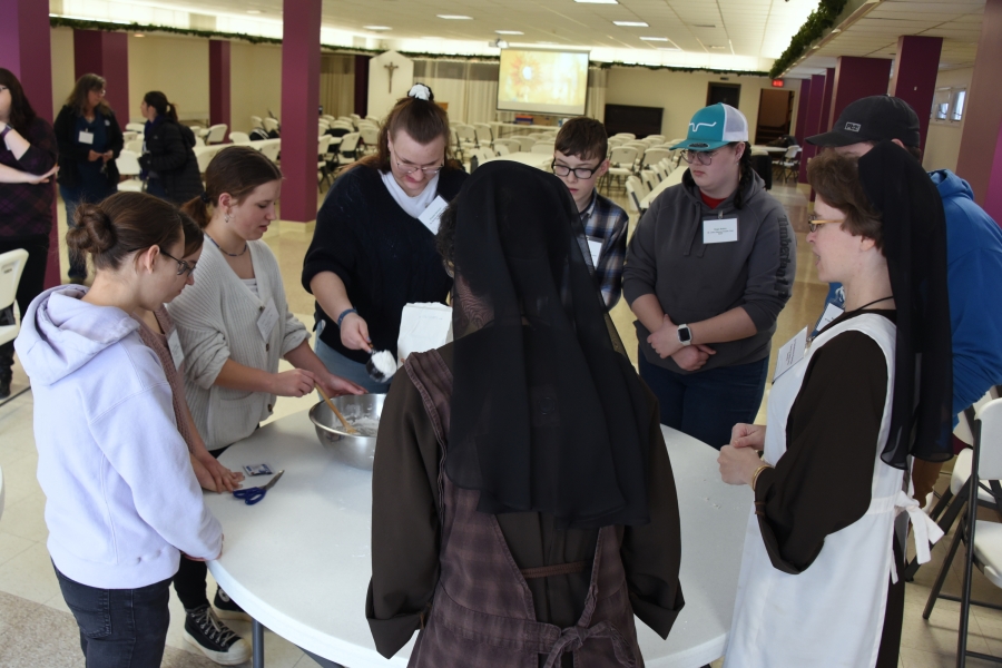 Group of teens and Franciscan sisters make pretzels.