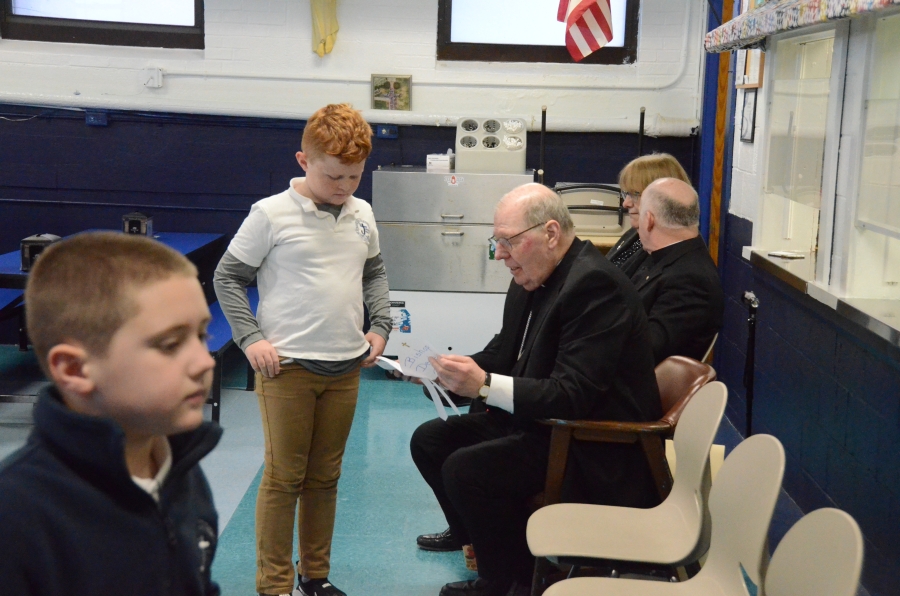 A student gives the bishop a card.
