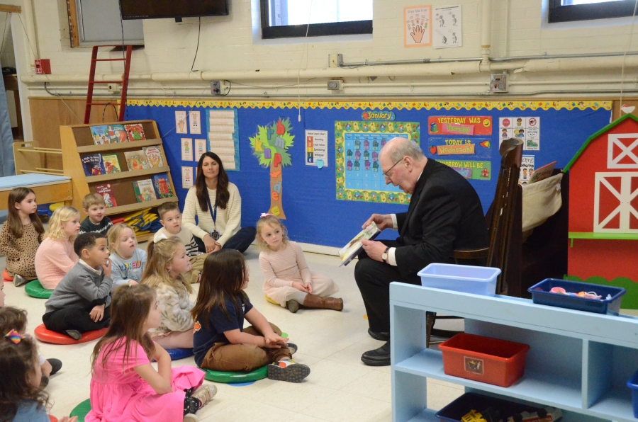 The bishop reads to students.