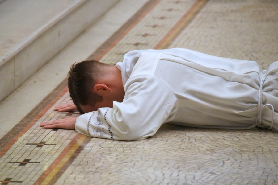Lying prostrate while the Litany of Saints is sung.