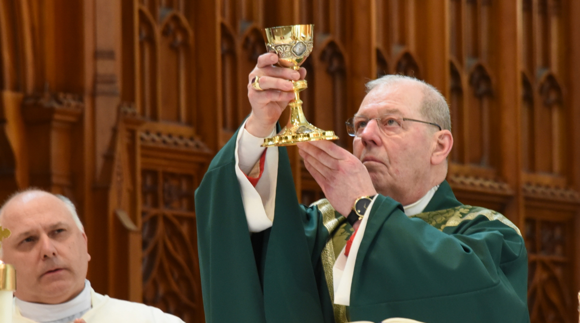 Bishop Robert Deeley holding up a chalice at the Basilica of Ss. Peter & Paul in Lewiston.