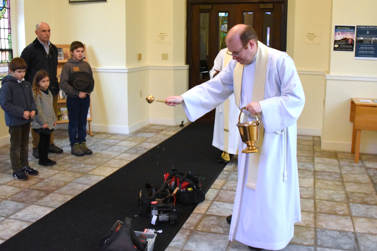 Father Kevin Upham sprinkles tools with holy water.